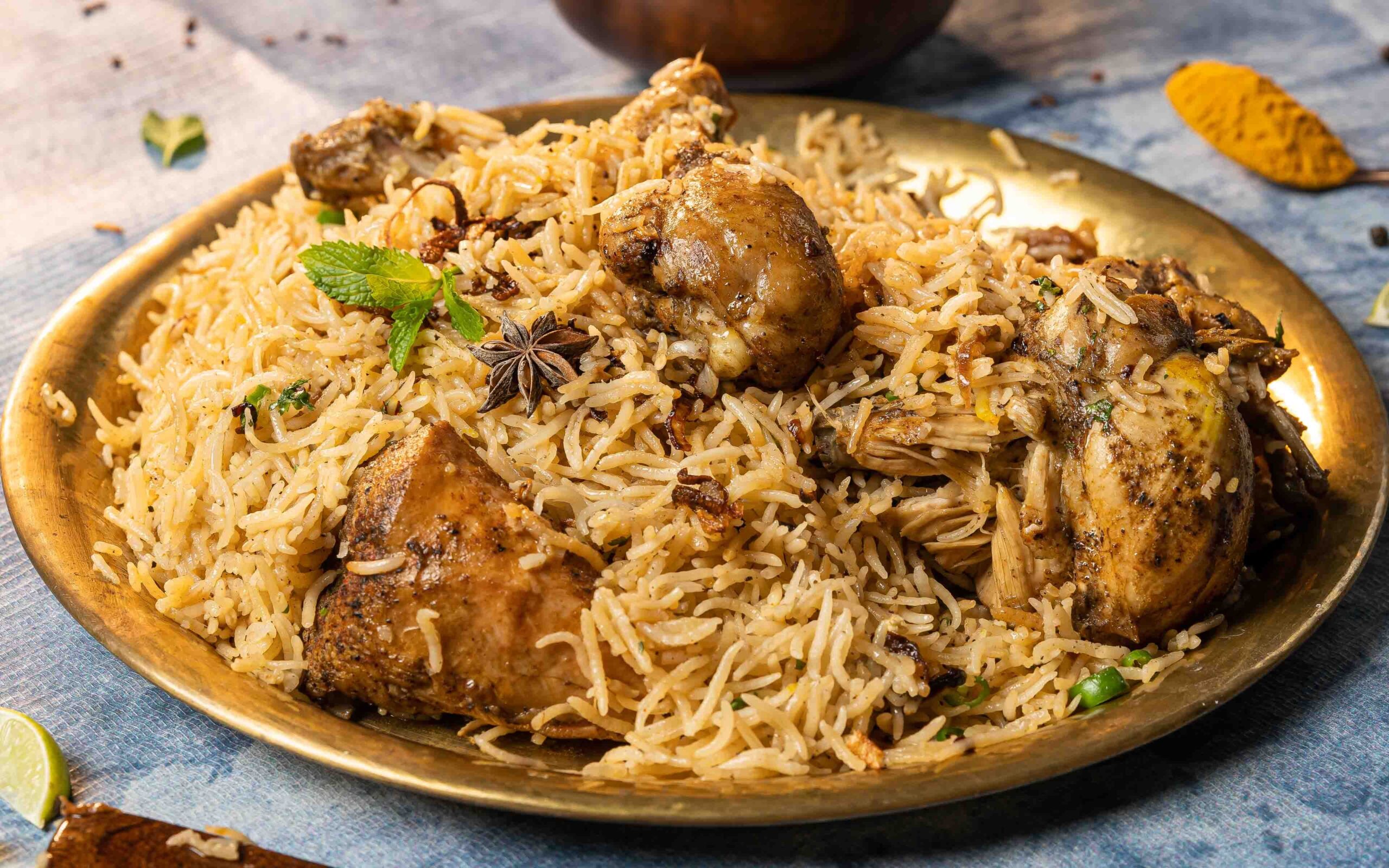 Close-up of aromatic chicken biryani served on a brass plate with garnishes, showcasing Indian culinary art.